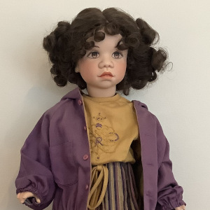 18-inch modern white Rudy doll with pigtails and purple and gold hooded jacket and striped skirt