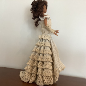 Tall, brown-skinned vinyl fashion doll in off-white crocheted dress