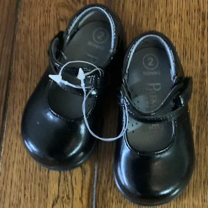 Black size-two baby shoes with double pleather strap held in place by a matching clasp