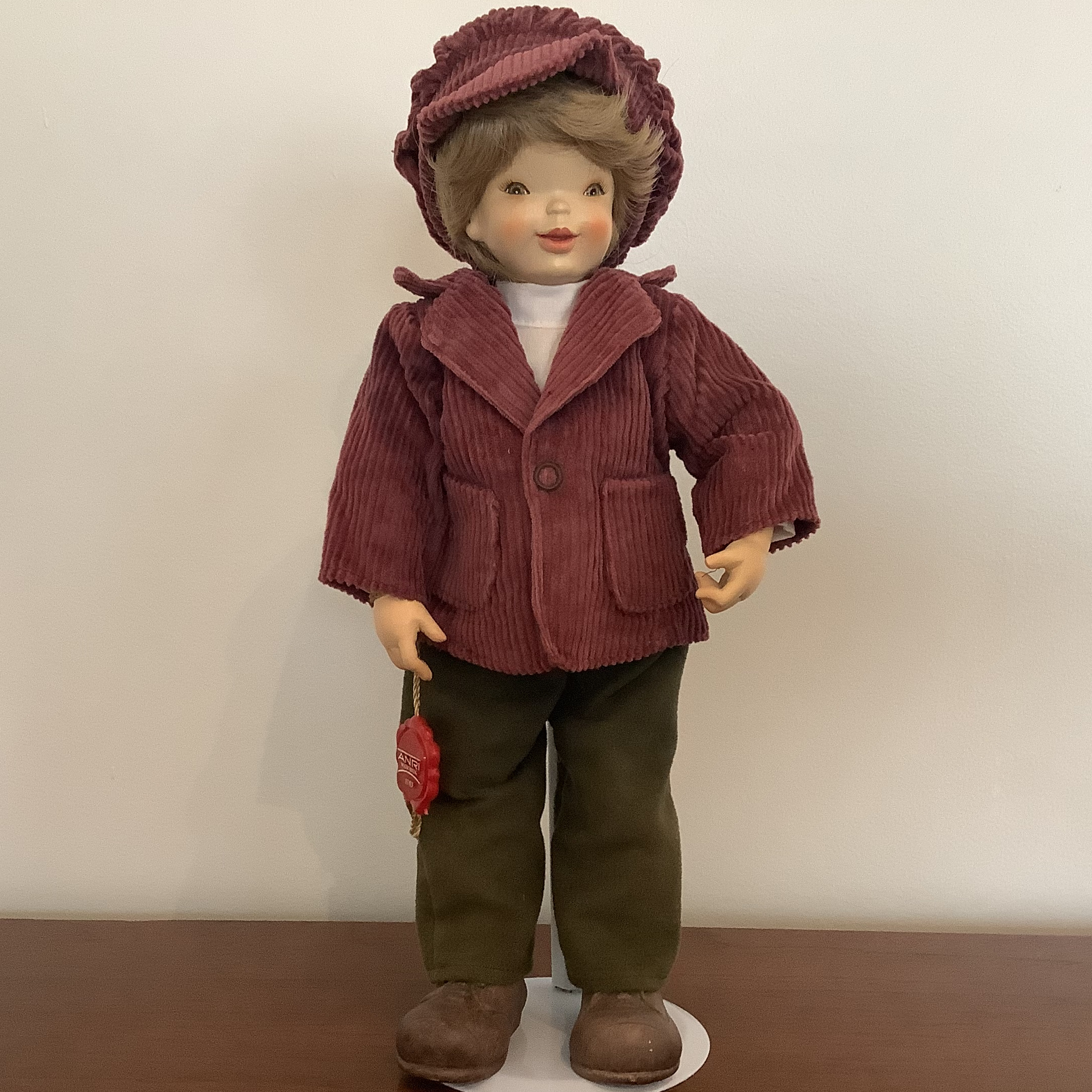 Handpainted wooden short-haired doll in matching burgundy corduroy jacket and hat with brown trousers