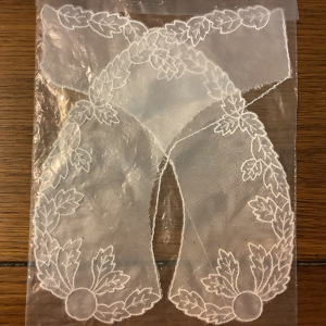 Collar in sheer white fabric with white embroidery; visible damage to inner seam allowance on one side