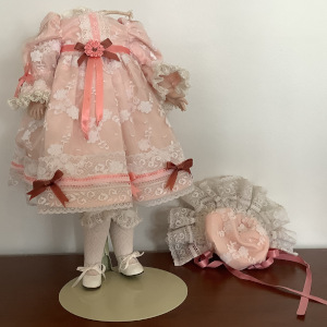 Headless doll body wearing a pink dress with lace and ribbon overlay