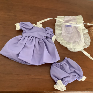 Purple dress with gathered skirt and matching bloomers, partially obscured by a white apron with lace edges