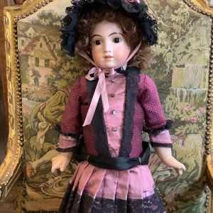 Medium-sized white doll with dark hair and eyes, wearing a pink and black suit