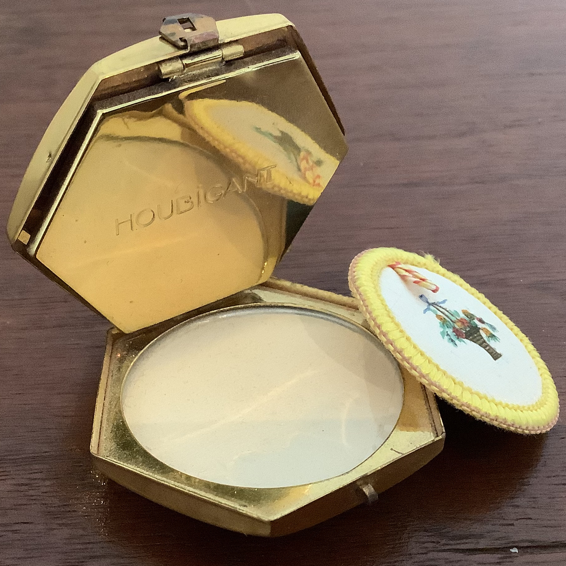 Open compact revealing beige powder and a powder puff
