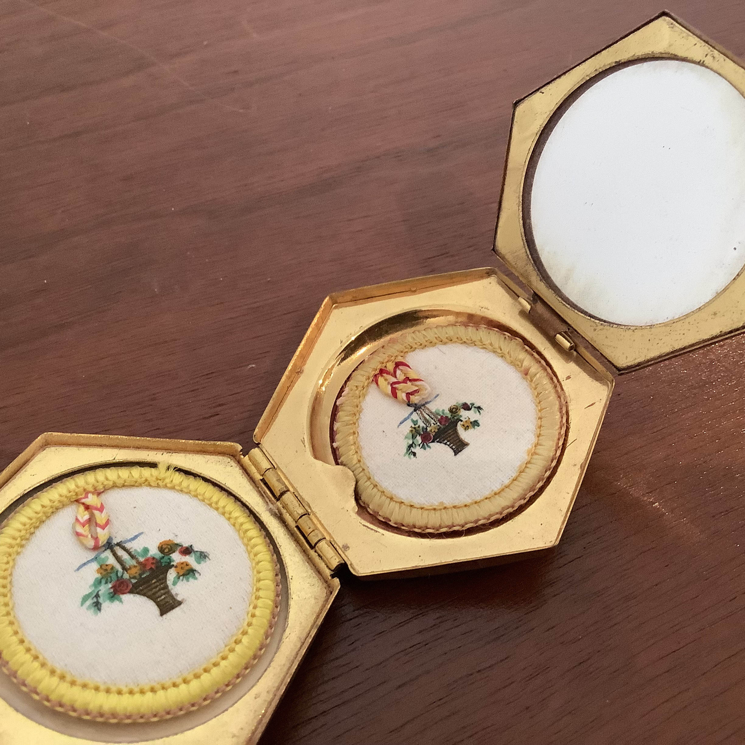 Open compact revealing three compartments: two powder puffs and a mirror