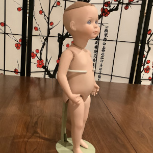 Light-skinned modern doll with painted face and blue glass eyes with no clothing