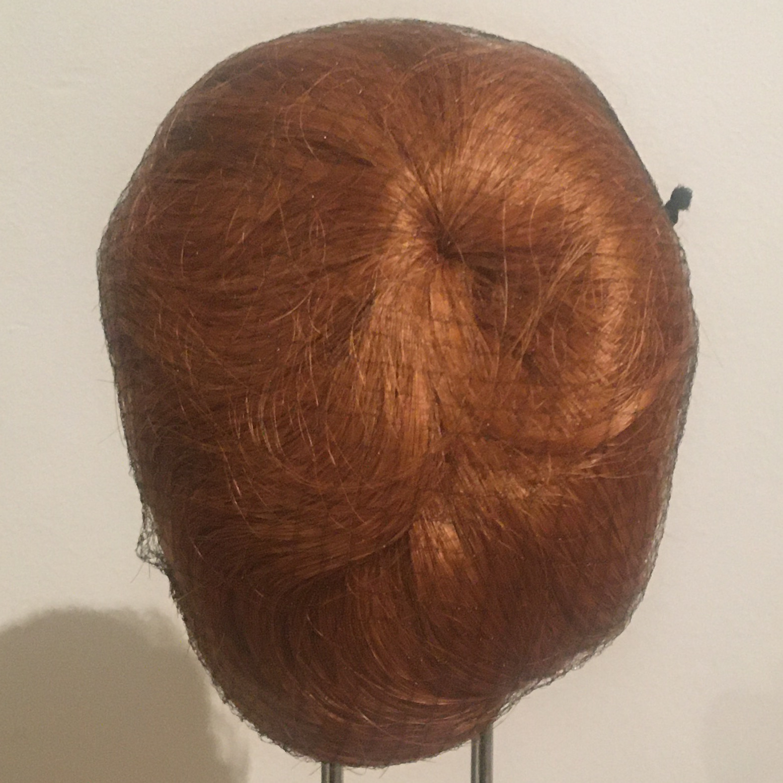 Dark red wig with medium short straight hair contained within a hair net