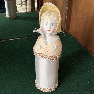 Small 8-inch half doll with white plinth and beige shawl. Painted eyes and hair.