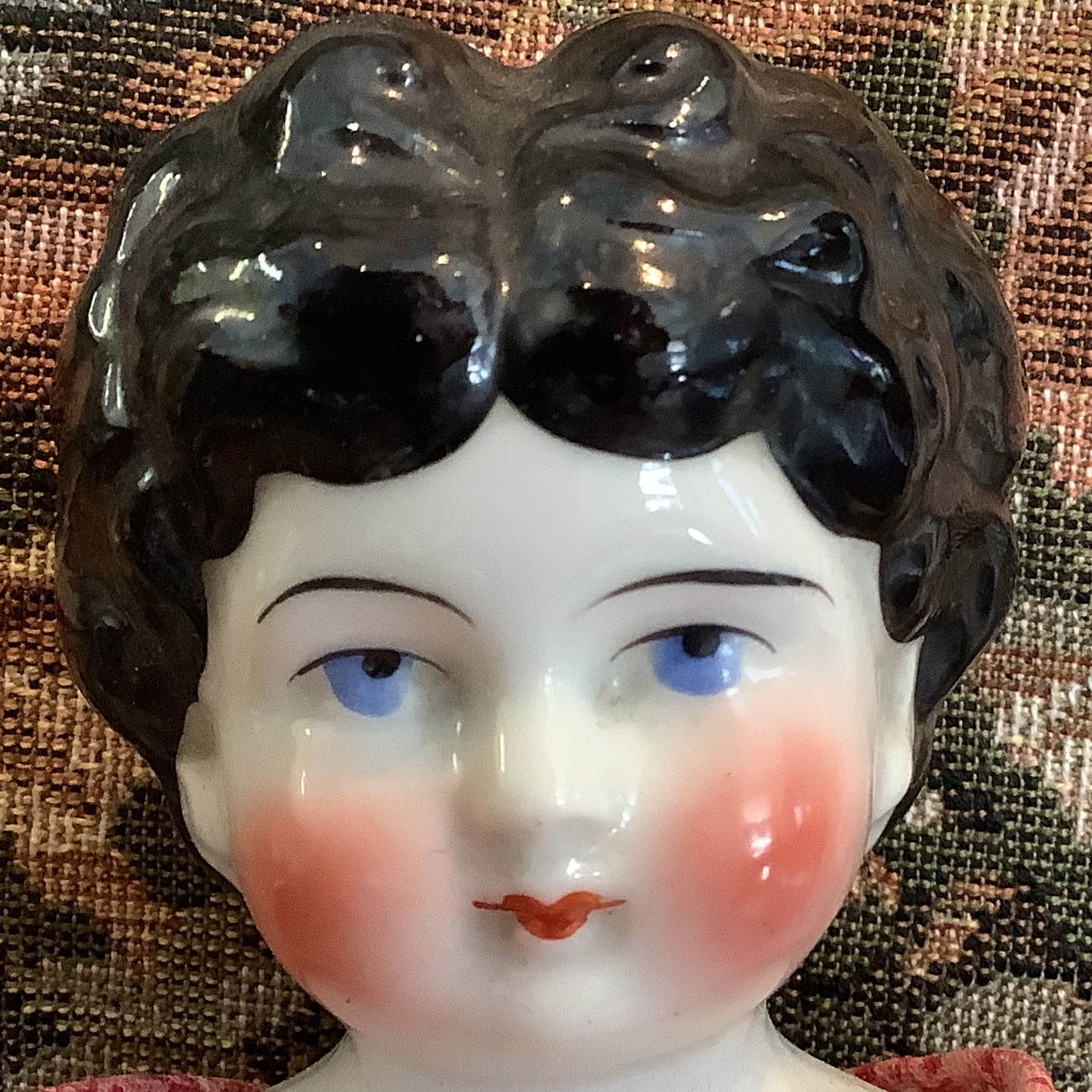 China doll with molded black hair and white skin in pink and red calico dress with tiny flowers