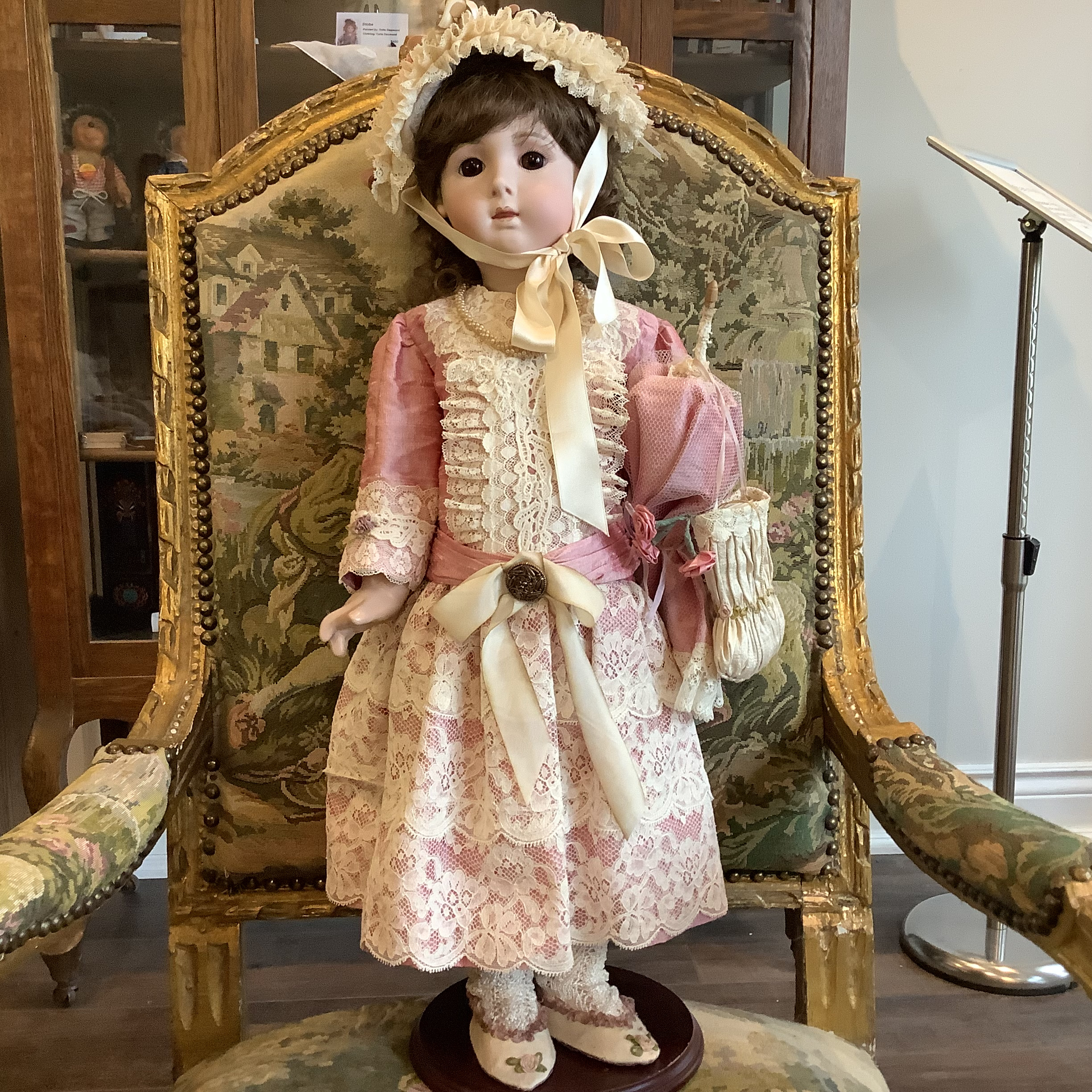 Small, white-haired doll in Tudor hat and short brown dress with lace cuffs.