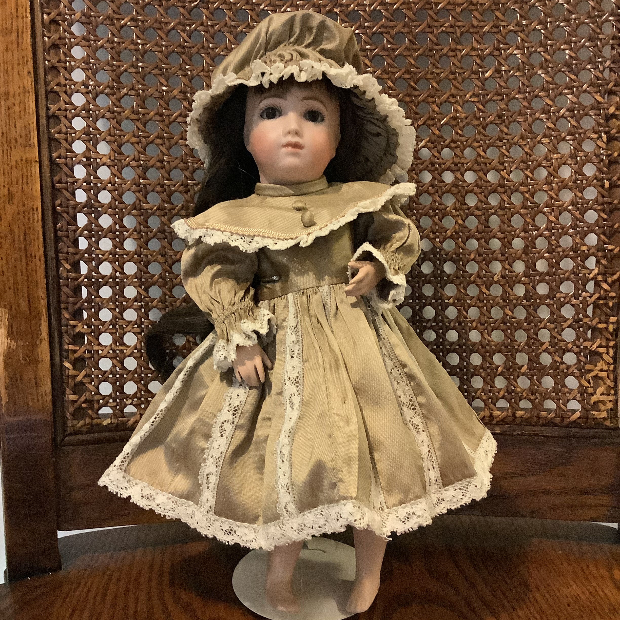 Small porelain doll in green silk dress with white lace trim and no shoes, with wavy chocolate brown hair